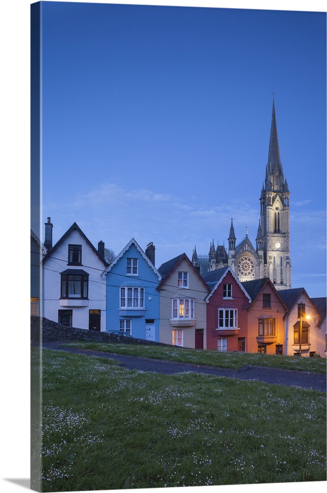 Ireland, County Cork, Cobh, Deck of Cards hillside houses and St. Colman's Cathedral, dusk.