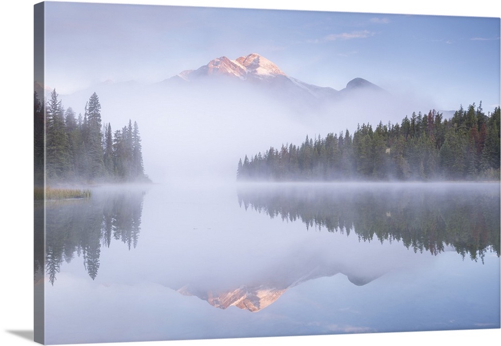 A mist shrouded Pyramid Mountain reflected in Pyramid Lake at dawn, Jasper National Park, Alberta, Canada.