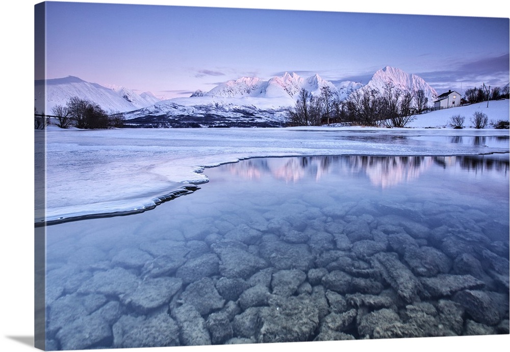 Snowy peaks are reflected in the frozen Lake Jaegervatnet at sunset Stortind Lyngen Alps Tromsa - Lapland Norway Europe.