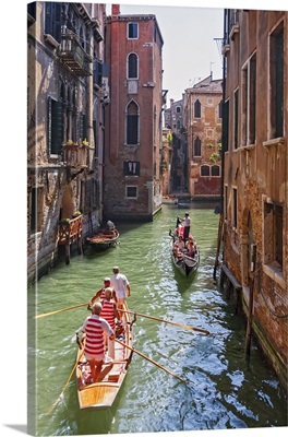 Local gondaliers row their traditional boat in one of Cannaregios canals, Venice, Italy