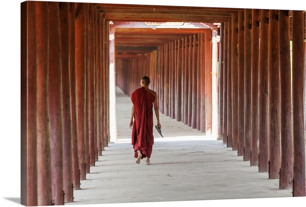 Monk in walkway of wooden pillars to temple, Salay, Myanmar, (Burma)
