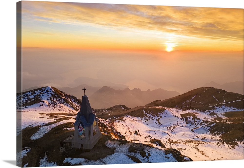 Aerial view of a winter sunset over Monumento al Redentore chapel on the top of Mount Mount Guglielmo. Zone, Brescia provi...