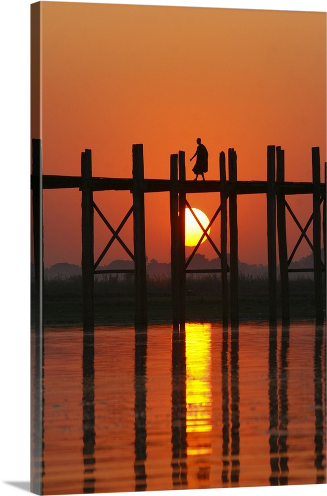 Myanmar (Burma), Amarapura, Taungthaman Lake, U Bein's Bridge. A monk walking home at sunset over U Bein's Bridge, over 20...