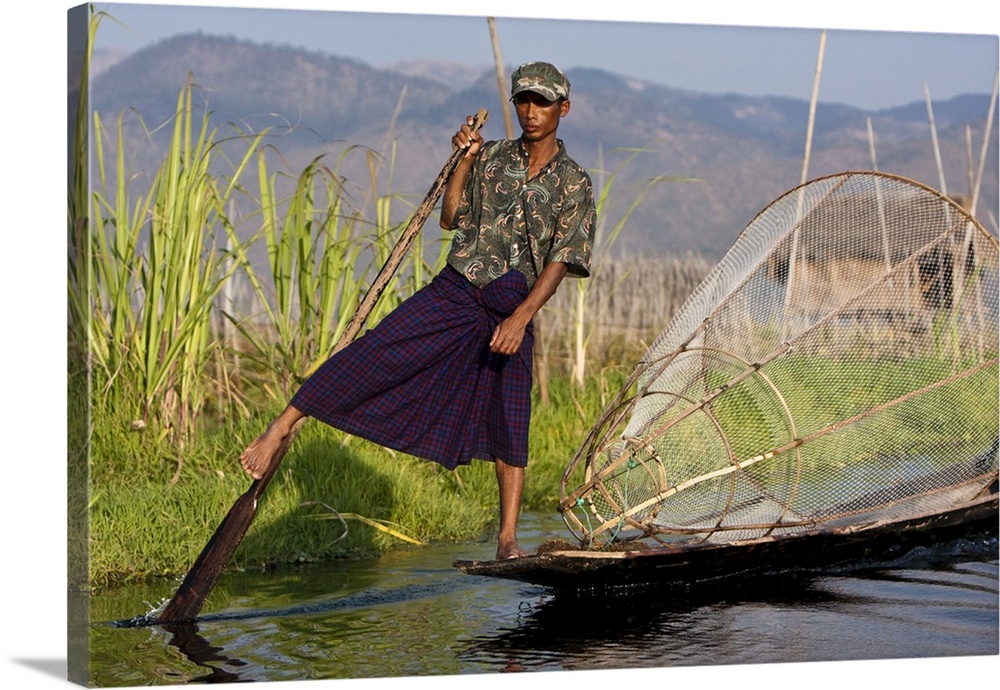 Myanmar, Inle Lake. Intha fisherman with traditional conical fish net, gently paddling his flat-bottomed boat home.