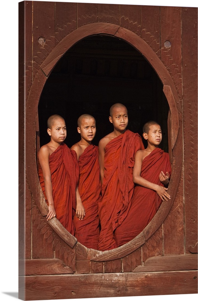 Myanmar, Burma, Nyaungshwe. Young novice monks standing at a wooden oval window, Shwe Yaunghwe Kyaung monastery.