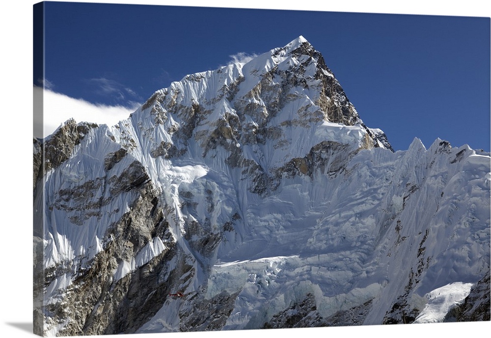 Nepal, Everest Region, Khumbu Valley. A helicopter having carried out a rescue from the Everest Base Camp is dwarfed by th...