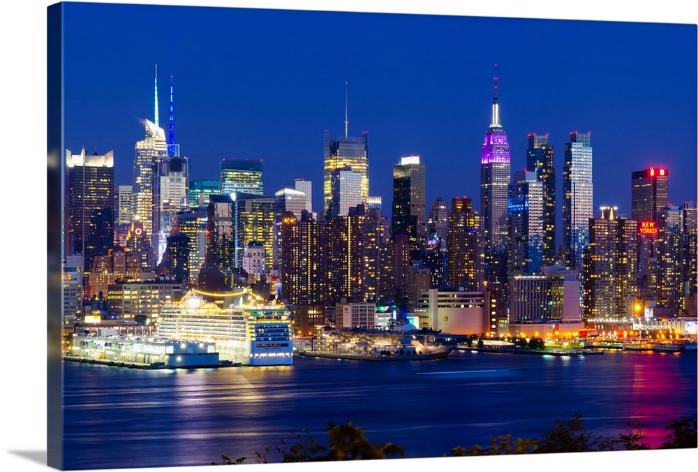 Canvas print of the NYC cityscape lit up in colored lights along a waterfront.
