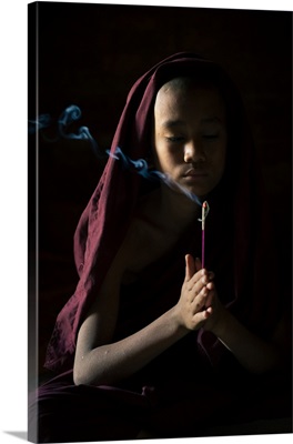 Novice Monk Holding A Lit Incense Stick While Praying Inside A Temple, Bagan, Myanmar