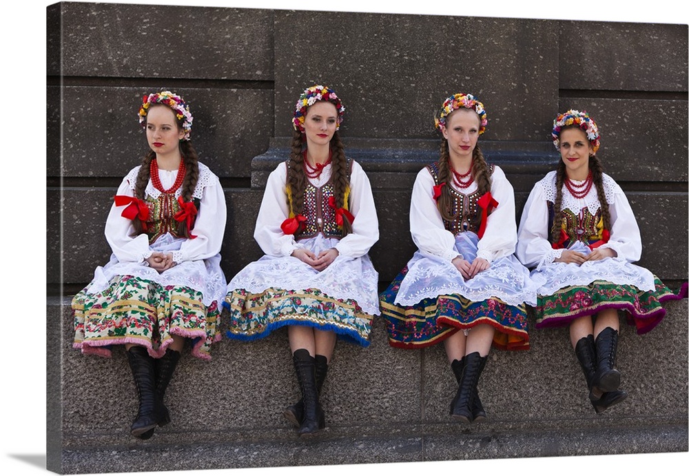 Poland, Cracow. Polish girls in traditional dress sitting at the base of the statue of Adam Mickiewicz, preparing to dance...