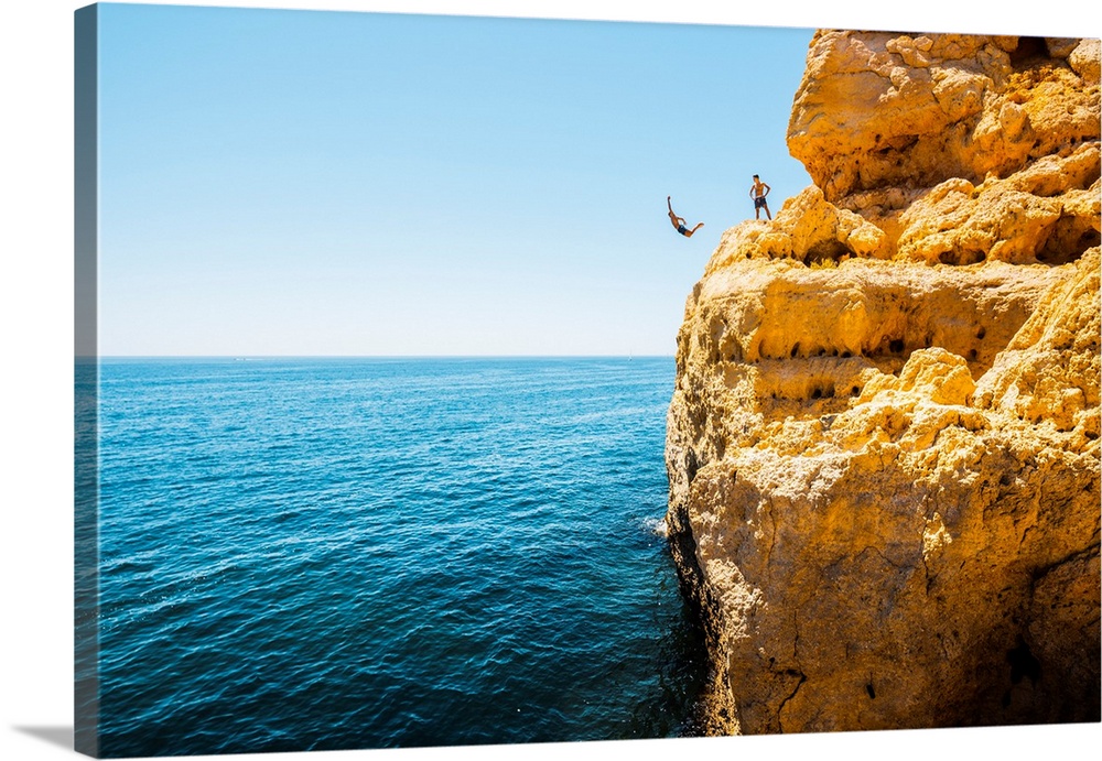 Portugal, Algarve, Faro district, Lagoa, Carvoeiro, Algar Seco. Boys jumping off the cliff into the Atlantic Ocean.