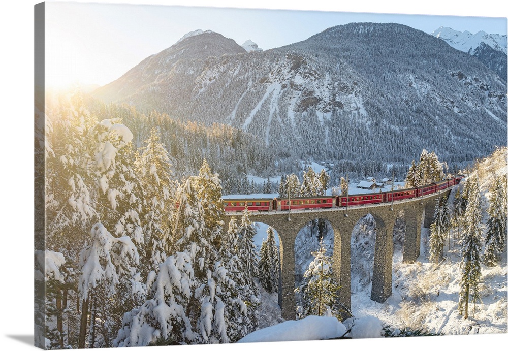 Red train traveling in the winter snowy landscape from Filisur to Tiefencastel railway station, aerial view, Graubunden, S...