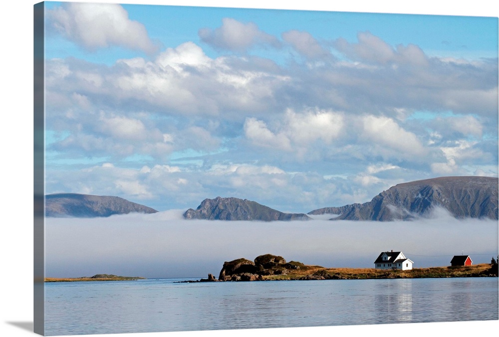 Remote house on the island of Langoya in the Vesteralen Islands, Norway, with sea fog and mountains on Andoya in the backg...