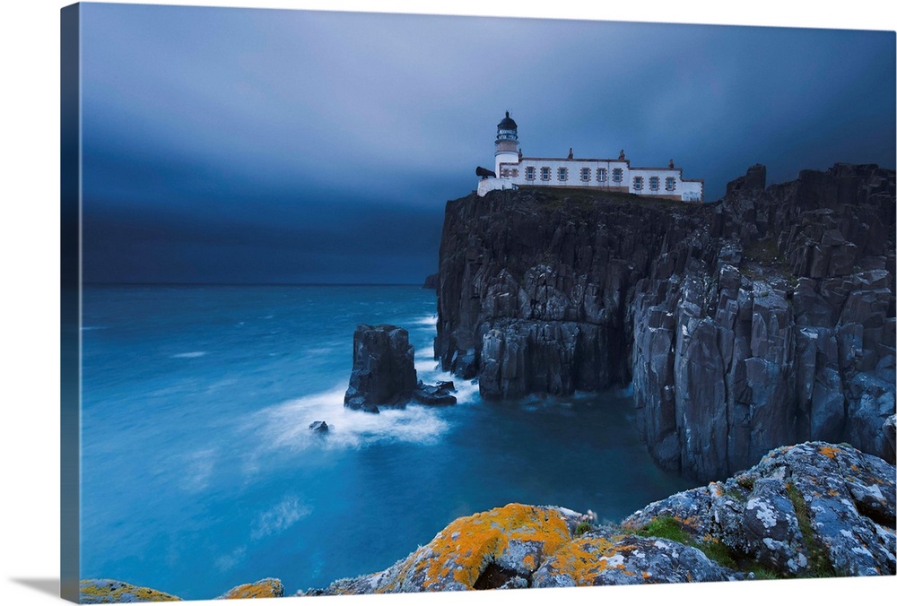 Rocky cliff on the sea, with a lighthouse on the reef, Neist Point, Isle of Skye, Scotland, UK.