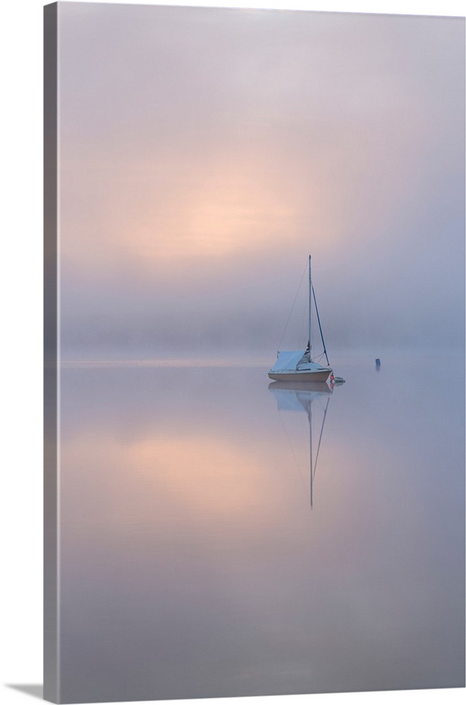 Sailing boat in misty conditions at dawn on a reflective Wimbleball Lake, Exmoor National Park, Somerset, England. Spring ...