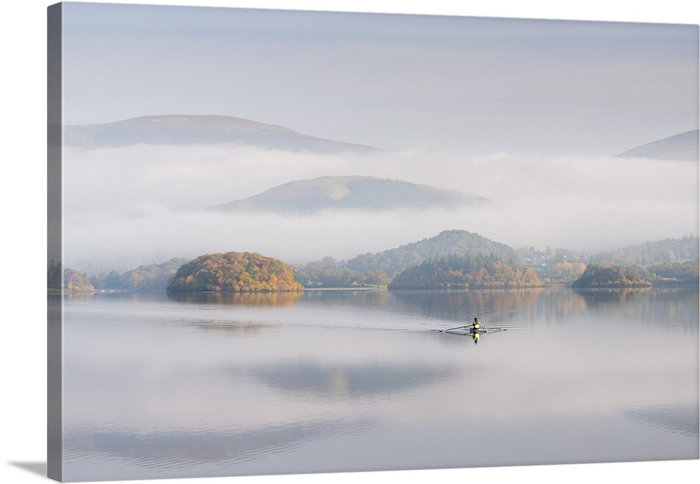 Single sculler rowing across a misty Derwent Water at dawn, Lake District, Cumbria, England. Autumn (October) 2016.