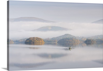 Single sculler rowing across a misty Derwent Water, Lake District, Cumbria, England.