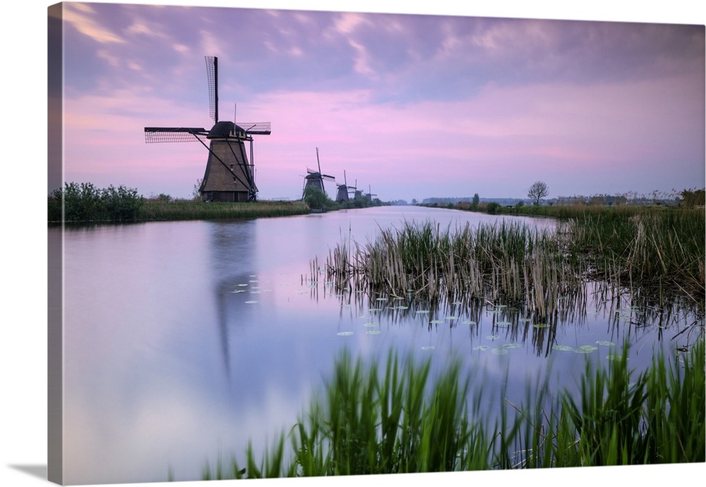 Sky is tinged with purple at dawn on the windmills reflected in the canal Kinderdijk Rotterdam South Holland Netherland Eu...