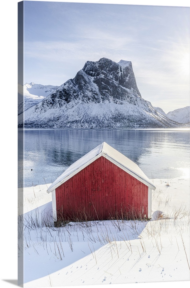 Snowy rorbu overlooking the frozen sea, Bergsfjorden, Senja, Troms county, Norway