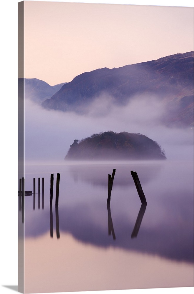 Old wooden jetty and St Herbert's Island on Derwent Water at dawn on a misty morning, Lake District National Park, Cumbria...