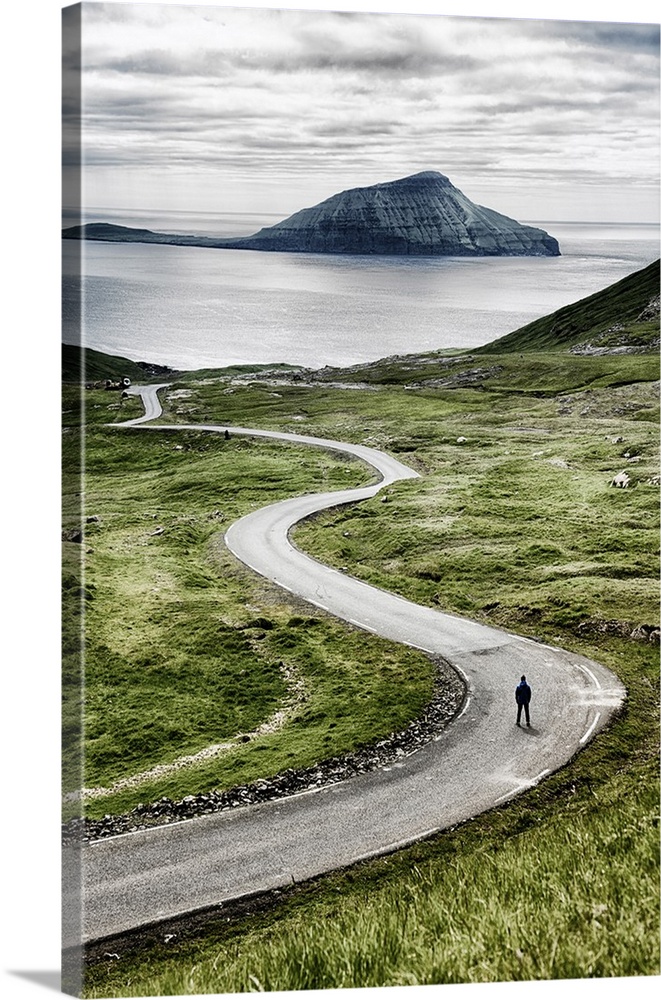 Stremnoy island, Faroe Islands, Denmark. Man standing on a bending road.