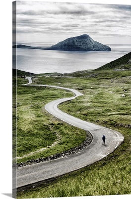 Stremnoy island, Faroe Islands, Denmark. Man standing on a bending road