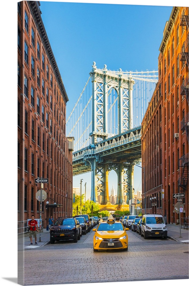 Taxi passing under the Manhattan bridge with the Empire state building framed in the bridge, New York, USA.