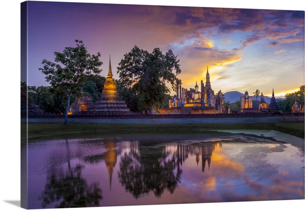 Thailand, Sukhothai province, Sukhothai,UNESCO World Heritage site, Wat Mahathat reflected in lake at dusk.