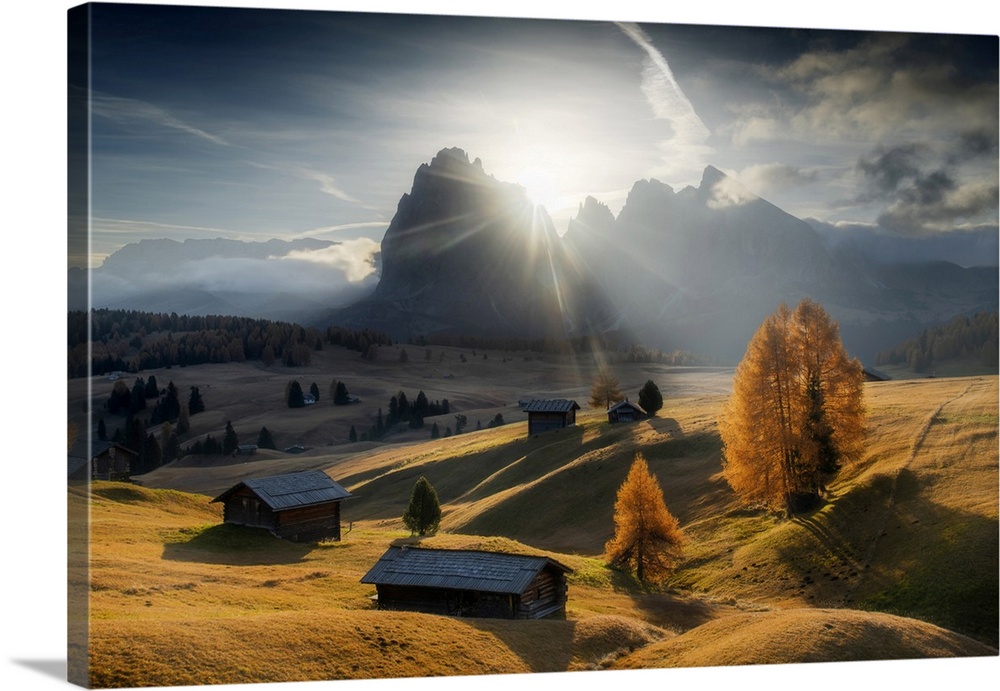 The lonely cabins of the Alpe di Siusi (Seiser Alm) during a sunny autumn morning, with the mountains in the background. D...