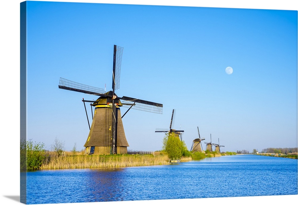 Netherlands, South Holland, Kinderdijk, UNESCO World Heritage Site. The moon rises above historic Dutch windmills on the p...