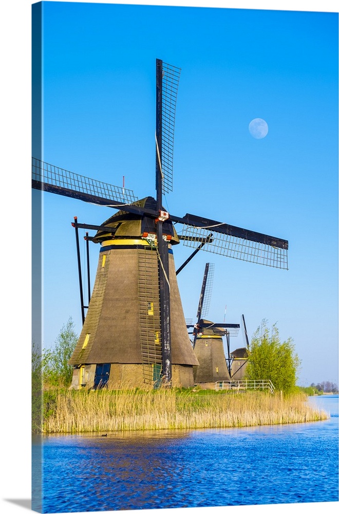 Netherlands, South Holland, Kinderdijk, UNESCO World Heritage Site. The moon rises above historic Dutch windmills on the p...
