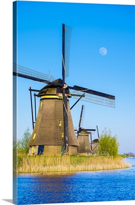 The moon rises above historic Dutch windmills on the polders, Netherlands
