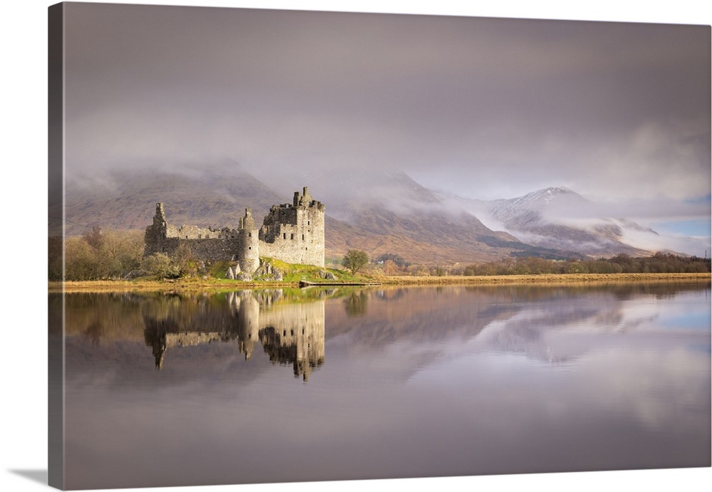 The ruins of Kilchurn Castle reflected in Loch Awe at dawn on a misty morning in the Scottish Highlands, Argyll and Bute, ...
