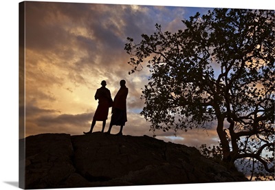 Two Maasai men silhouetted on a hill at sunset