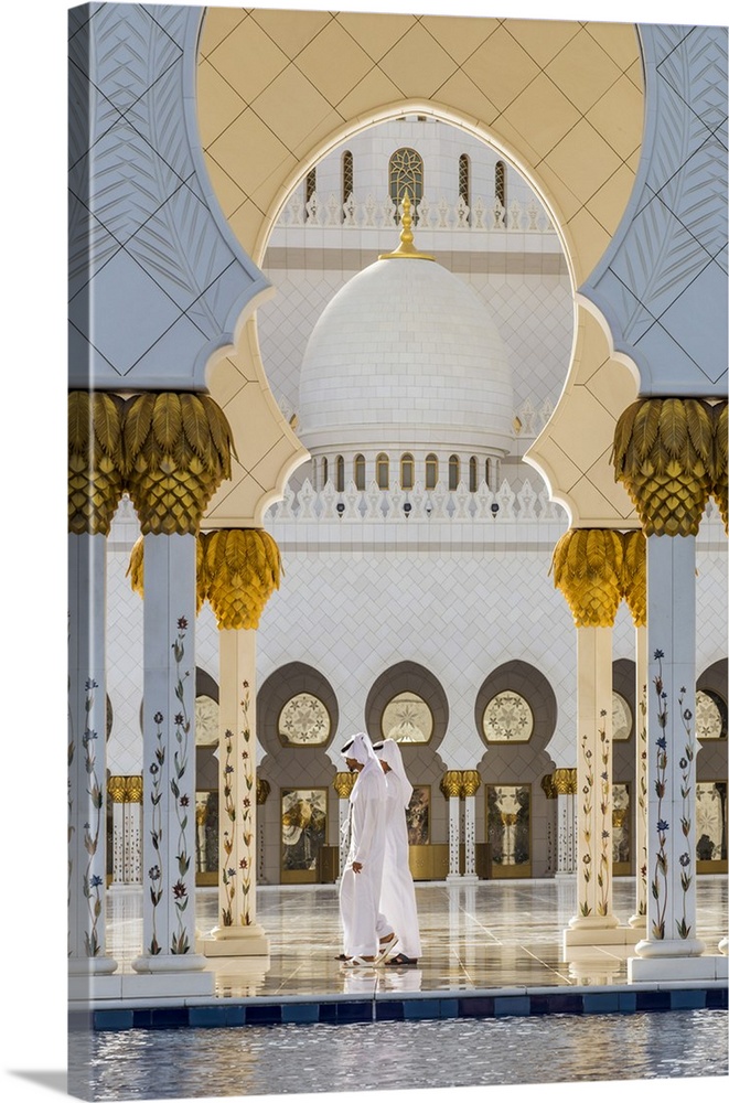 Two Middle Eastern men traditionally dressed walking in the courtyard of the Sheikh Zayed Mosque, Abu Dhabi, United Arab E...