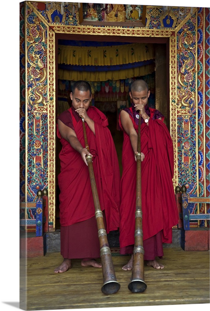 Two monks blow long horns called dung-chen, at the temple of Wangdue Phodrang Dzong (fortress). These copper or brass inst...