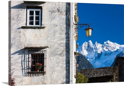 Typical alpine house and street lantern frame the snowy peaks Soglio Bregaglia Valley