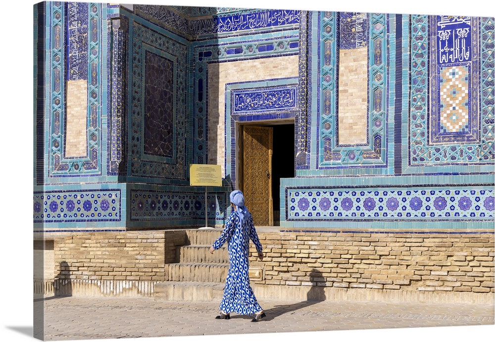Uzbekistan, Samarkand, Shah-i-Zinda, Tomb Street of 11 Mausoleums, a local woman walks past one of the mausoleums.