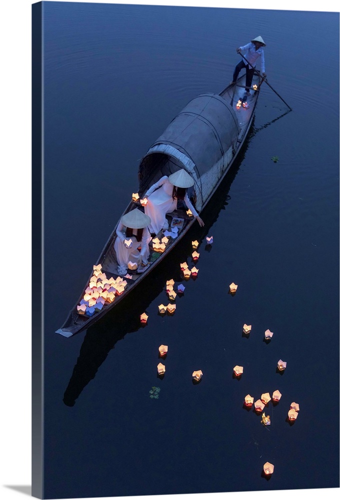 Vietnamese girls in Ao Dai dresses drop floating candles on a river in Hue to pray for the dead, Hue, Thua Thien-Hue provi...