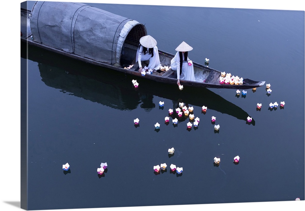 Vietnamese girls in Ao Dai dresses drop floating candles on a river in Hue to pray for the dead, Hue, Thua Thien-Hue provi...