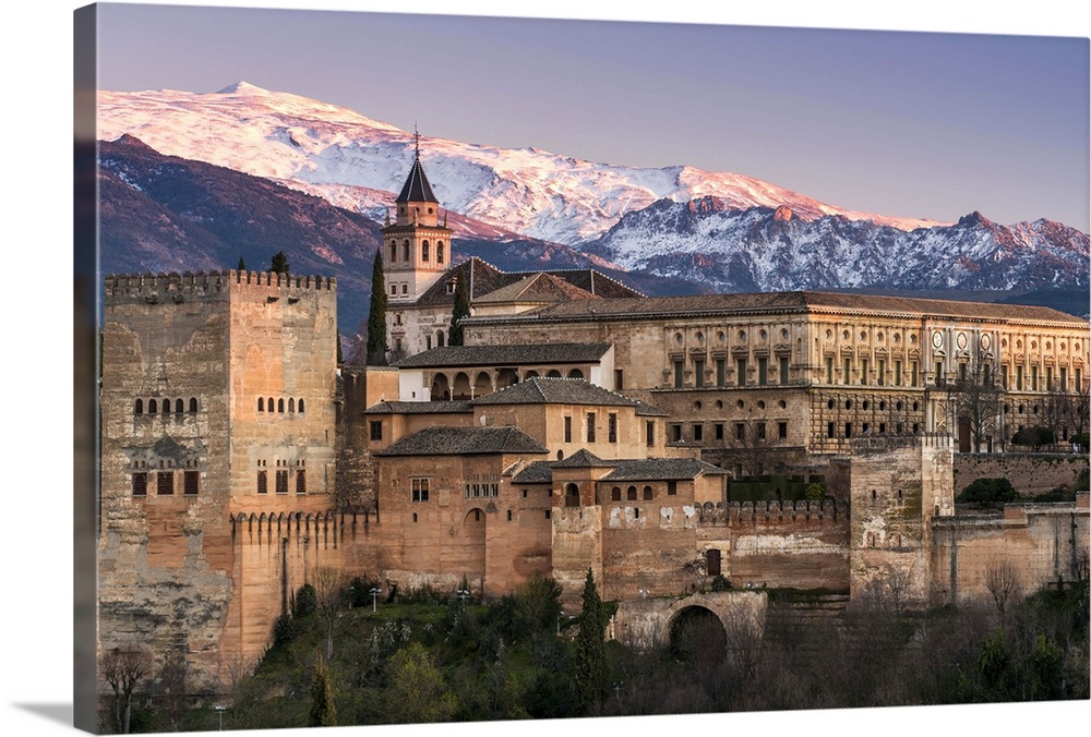 View at sunset of Alhambra palace with the snowy Sierra Nevada in the background, Granada, Andalusia, Spain.