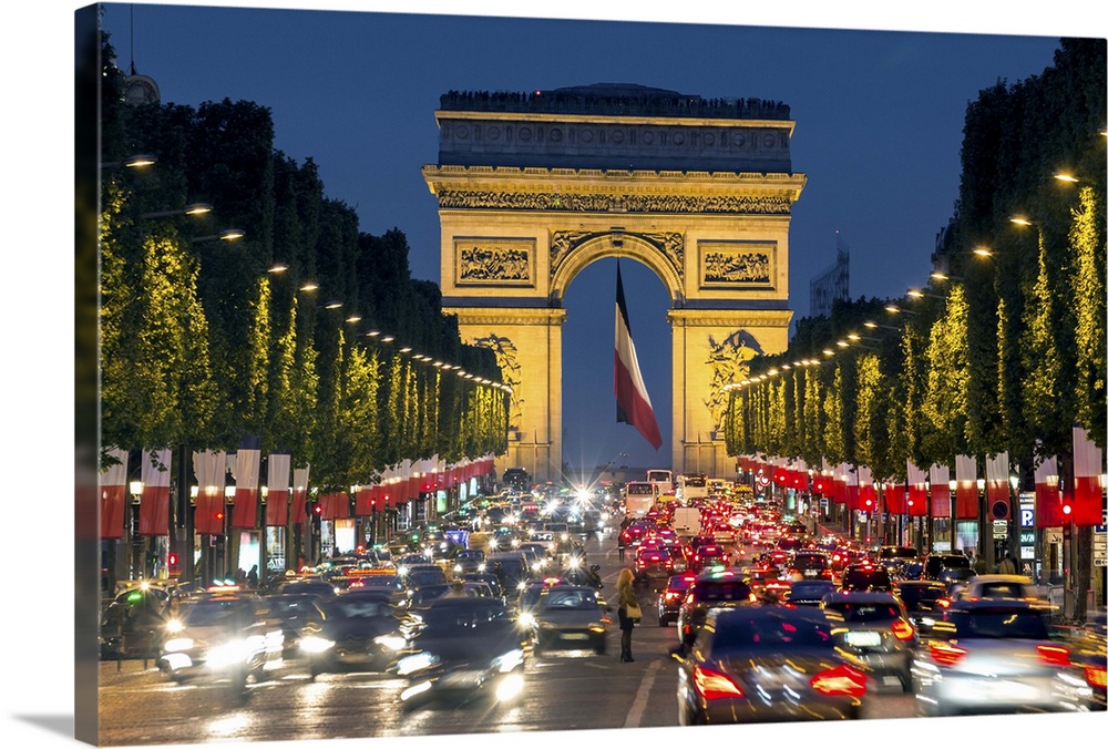 View down the Champs Elysees to the Arc de Triomphe, illuminated at dusk, Paris, France.
