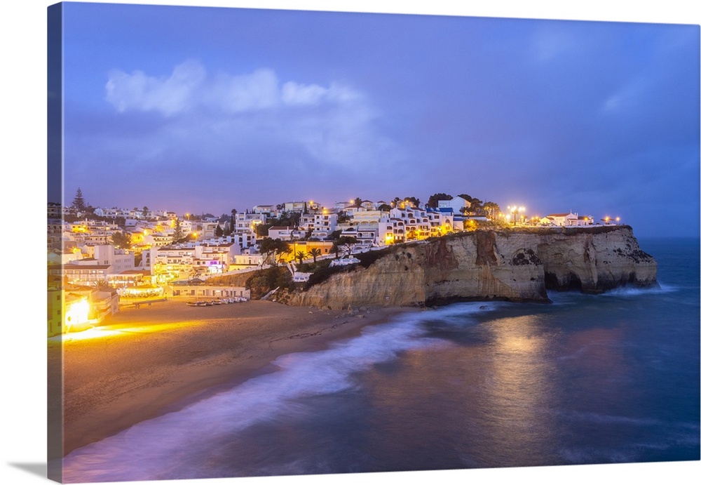 View of the lights of the village of Carvoeiro and its beach at blue hour. Lagoa municipality, Algarve, Portugal
