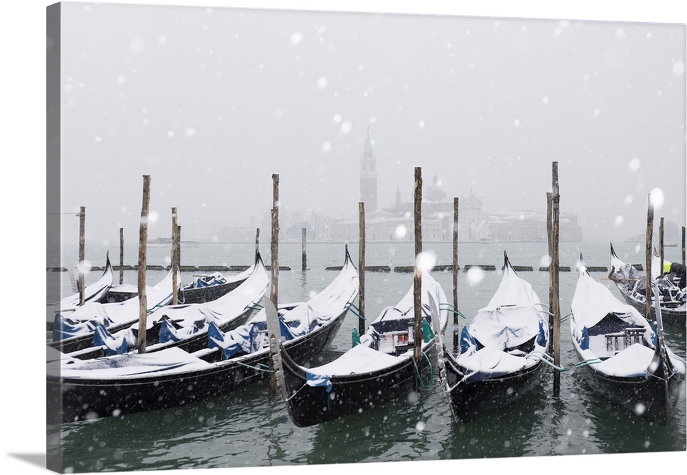 Winter snowfall in the city of Venice, gondolas covered by snow and in the background the San Giorgio Maggiore church, Ven...
