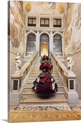 Woman in costume standing on staircase in Ca Segredo palace during Carnival, Venice