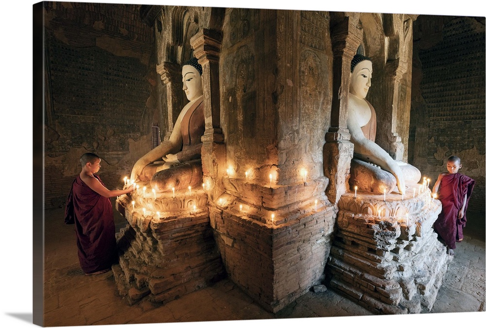 Young Buddhist monks pray in front of a statue of Buddha in a temple in Bagan, Myanmar.