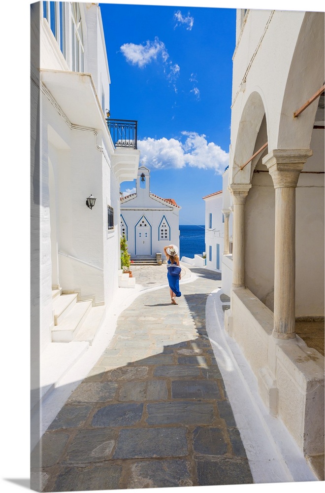 Young woman walking on the street that leads to the Church of St. Barbara, Andros, Cyclades archipelago, Greece, Europe (MR).