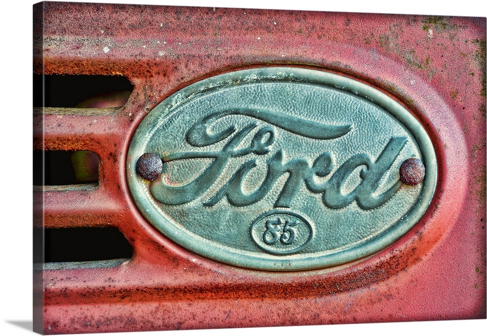 Oversized, horizontal photograph of a Ford emblem attached to an old, rusty 1930's Ford F38.