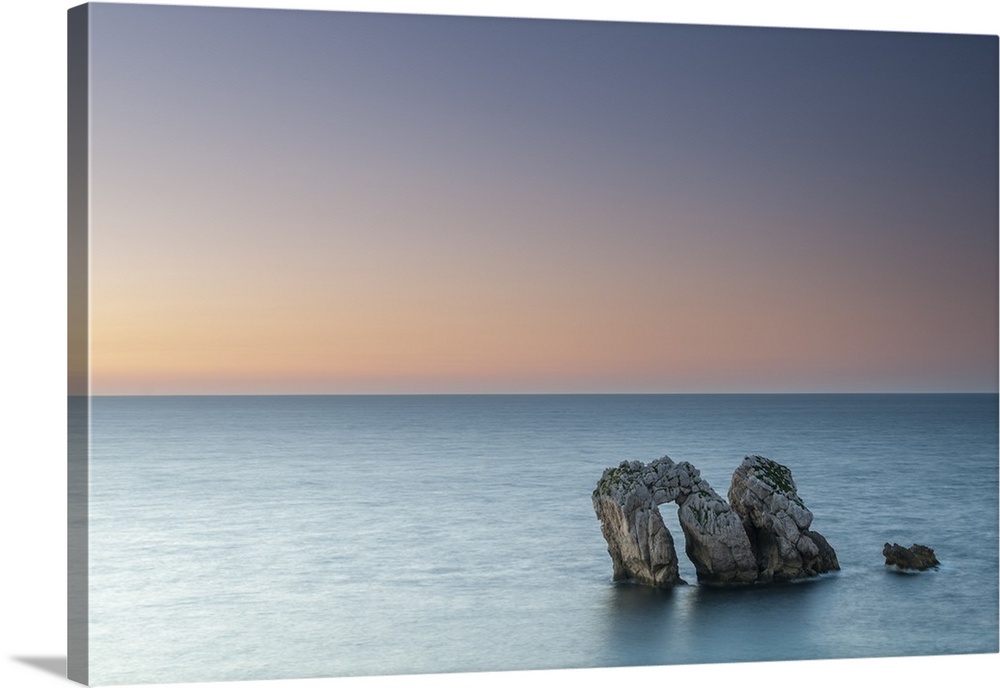 Archway boulders in a blue ocean at sunset.