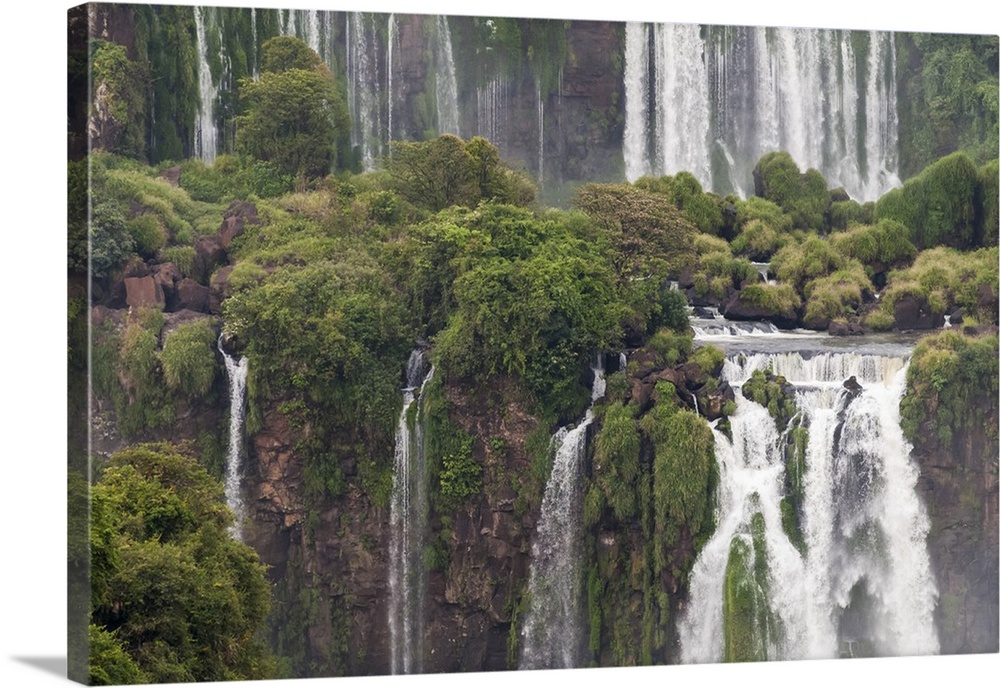 Photograph of massive waterfalls flowing down over lush jungle cliffs.