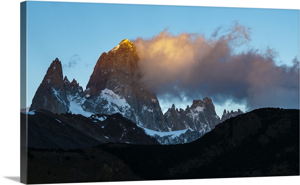 Photograph of golden mountain spires in South America illuminated by the setting sun.